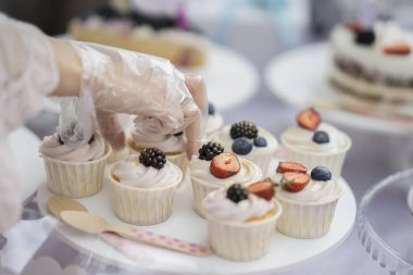 Farklı iştah açıcı tartlets, beyaz krem ve taze çok renkli meyveleri, yaz tatlı, pastacı, satıcı elleri ile kek sepeti