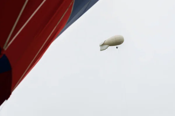 白は色鮮やかな赤、熱気球で近くに雨の日に灰色の空に熱気飛行船、飛行船です。膨脹可能な飛行船。現代の抽象的な背景。テキスト — ストック写真