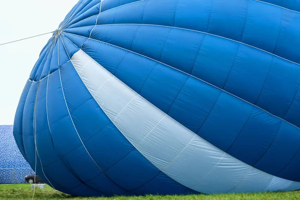 Uitzicht vanaf buiten een blauw-witte hete lucht ballon whan is opgeblazen voor vlucht naast auto — Stockfoto