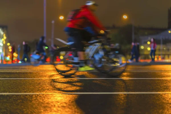 Jonge man biker fiets tijdens 's nachts op een stad straat. Abstracte wazig sport achtergrond — Stockfoto