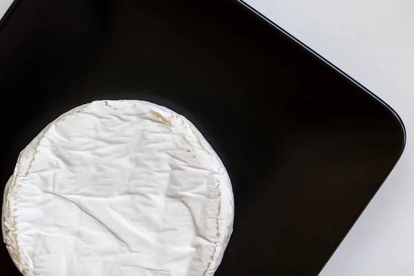 Head of camembert or brie cheese in black square plate, minimalism. Top view, copy space — Stock Photo, Image