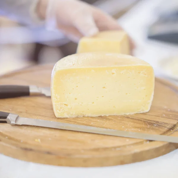 Cheese heads no mercado, vendedor vende queijo, mãos de vendedor em luvas. Foco seletivo. Produtos lácteos gastronômicos, cena real, mercado de alimentos, para fundo — Fotografia de Stock
