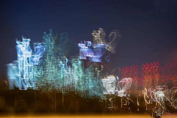 Bulanık gökdelenler koyu mavi gökyüzü karşı. Çok öykülü binalar gece, ışıklı Windows. Araba hızla modern şehir