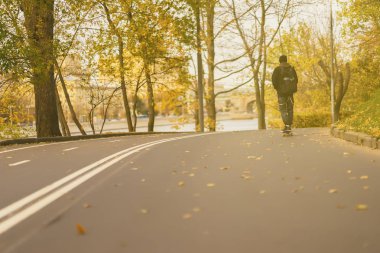 Park güneşli Ekim günü. Tanınmayan adamı, bize üzerinde kaykay, dağılan arasında yol üzerindeki longboard paten patenci terk etti. Kavram gençlik eğlence, spor, sonbahar