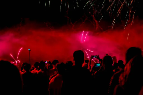 Desfocado fundo vívido com silhuetas irreconhecíveis de pessoas de volta para nós filmando um show em telefones e outros gadgets — Fotografia de Stock