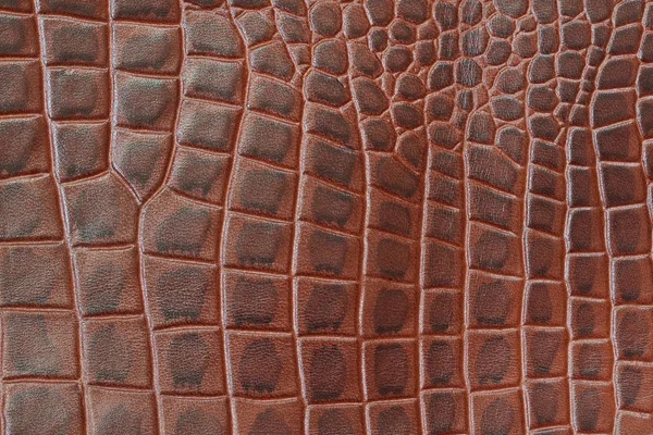Genuine leather texture backgroundr close-up, embossed under the skin a reptile, brown color print. Natural backdrop, copy space. Concept of shopping, manufacturing