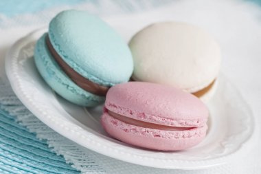 Farklı renkler ve beyaz bir tabak içinde farklı tatlar üç macaroons