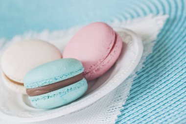 Farklı renkler ve farklı tatlar beyaz tabak, beyaz peçeteye üç macaroons.