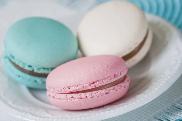 Tres macarrones de diferentes colores y diferentes gustos en un plato blanco, vista superior. Mañana romántica, regalo para la amada. Desayuno en San Valentín, Madres, Día de la Mujer. Fondo de la oferta —  Fotos de Stock