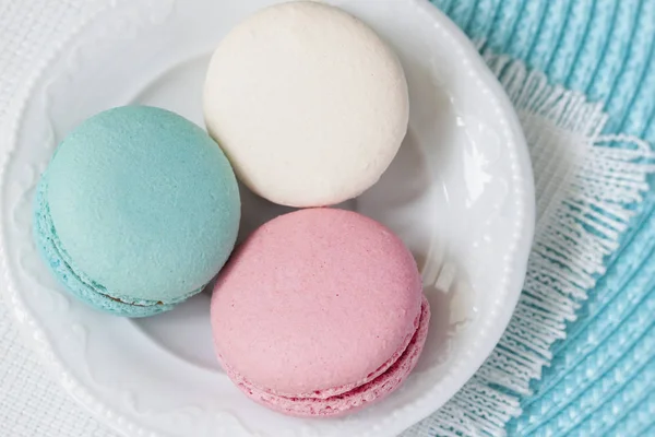 Tres macarrones de diferentes colores y diferentes gustos en un plato blanco, vista superior. Mañana romántica, regalo para la amada. Desayuno en San Valentín, Madres, Día de la mujer — Foto de Stock