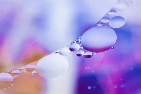 Colorful violet blue bubbles, macro oil drops in water surface. Abstract background, copy space