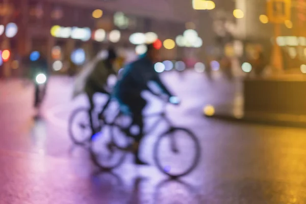 Abstract unrecognizable people, riding bikes, night city, illumination bokeh, motion blur. Healthy lifestyle, leisure activity concept.