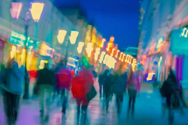 Helder wazig moderne stad 's nachts, onscherpe stedelijke bokeh stadslichten, silhouetten van de wandelende mensen. Abstract kleurrijke achtergrond — Stockfoto
