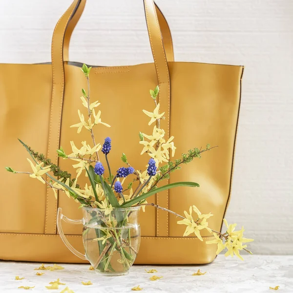 Bouquet von hellen bunten Blumen in Glasvase auf dem Hintergrund gelbe Handtasche Nahaufnahme. Konzept des Frühjahrs- oder Sommereinkaufs — Stockfoto