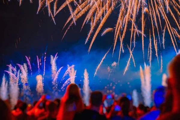 Abstract bright blurred background of silhouettes of unrecognizable people back to us celebrate holiday, watching and admiring firework