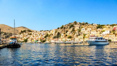 Yatlar, gemiler, renkli evler Symi adasındaki Ege Denizi 'nin antik limanında. Yunanistan