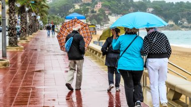 Lloret de Mar, Girona ili, Katalonya özerk bölgesi - 30 Eylül 2015: Yağmurlu havada kentin merkez seti boyunca yürüyen turistler