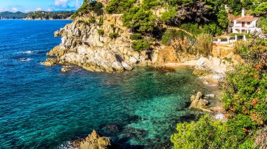 Costa Brava 'da, tatil köyü Lloret de Mar yakınlarındaki dik uçurumları olan bir körfez. Pipolu bir ev. Girona Eyaleti, Katalonya Özerk Topluluğu, İspanya