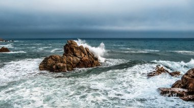 Dalgalar Akdeniz 'deki kayalara karşı savaşıyor. Lloret de Mar, Girona ili, Katalonya Özerk Bölgesi, İspanya