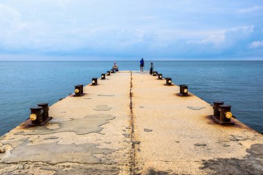 Yürekli bir iskele. Arka planda iki balıkçı var. Arka plan FOCUS 'ta değil..