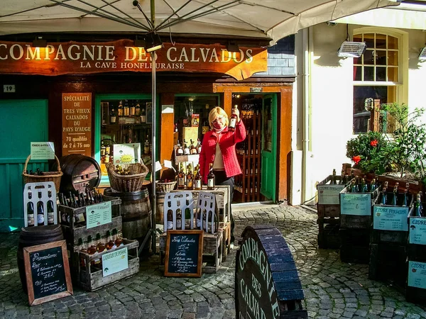 Honfleur, Fransa - 20 Ekim 2005: Normandiya 'nın gastronomik sembollerinden biri olan Calvados satan dükkan barı. Bir kadın elinde bu içeceğin şişelerinden birini tutuyor..