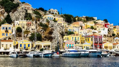 Simi şehrindeki körfezin kıyısındaki çok renkli evler Ege Denizi 'ndeki Yunan adasında aynı isimde.