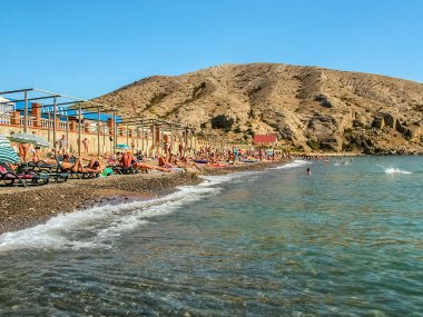 Sudak, Kırım - 14 Eylül 2010: Karadeniz. Cape Alchak yakınlarındaki şehir çakıl taşı plajı. Bir sürü banyo ve güneşlenen turistler. Güneşli açık hava.