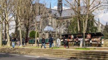 Paris, Fransa - 24 Mart 2014: Notre Dame de Paris 'in arka planına karşı Montebello gezinti alanı (Quai de Montebello) boyunca ikinci el kitapçı dükkanları boyunca geçenler.