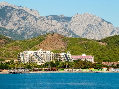 Camyuva, Türkiye - 19 Ekim 2017: Antalya 'nın Kemer bölgesindeki Akdeniz kıyısında Taurus Dağları' nın zeminine karşı şık bir otel