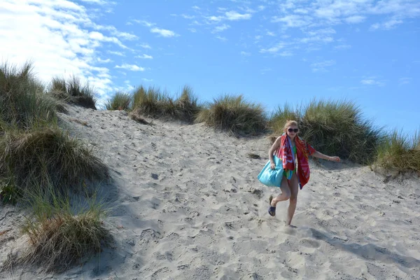 Девушка с плавающими штуками бежит по песчаным дюнам — стоковое фото