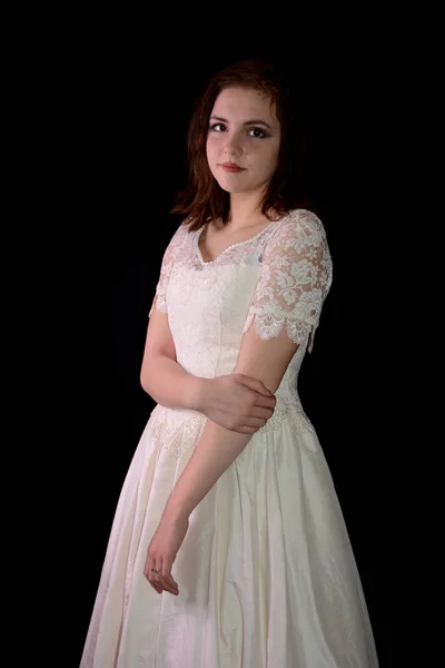 Молодая женщина в белом платье стоит на черном фоне — стоковое фото