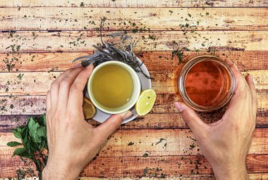 Limonlu ve doğal ballı sağlıklı salvia çayı sonbaharda soğuk günlerde bağışıklığın korunması için idealdir. Ellerinin yanında nane yaprakları ve ezilmiş ısırgan otları var. Bitkisellik kavramı