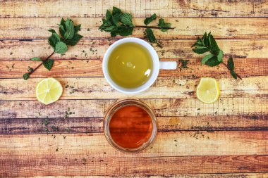Tahta masanın üzerinde çeşitli otlar bulunan bir fincan bitki çayı. Limonlu doğal bal soğuk günler için idealdir. Bitkisellik ve bağışıklık kavramı. Sıcak içecek hastalığın karşısında