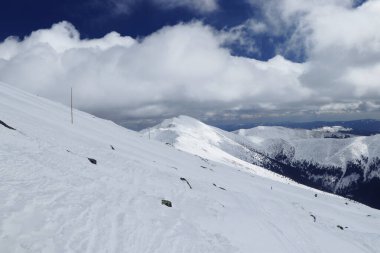 Karlı Chopok ve Dumbier dağlarının cennet manzarası. Karların altındaki dağların zirvesi. Alplerde sakin bir öğleden sonra. Batı Low Tatras 'taki Vajskovska vadisi. Beyaz bulutlarla kayak yamacı ve gölgelerle oynamak
