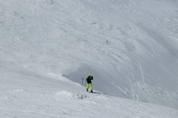 Turista v Alpách fotografuje údolí pod ním. Švýcarské Alpy a jen jeden freeride muž. Mladý chlapec sjezd svahu a zastavit před hranou a vzít telefon a udělat nějaké fotky. Zimní ráj — Stock fotografie