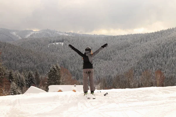 Rapariga respira fundo e exala ar das montanhas. esquiador profissional do sexo feminino desfrutar de uma vista para o vale. A esquiadora está a esticar os braços para o lado. Desfrute de uma liberdade de trabalho — Fotografia de Stock
