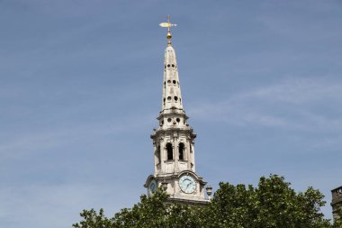 Londra 'daki ağaçlar arasında unutulmuş kilise kulesi. Orta çağdan kalma tarihi bir anıt. Kule güzel bir altın kuşla bitiyor. Ortasında mavi arkaplanı olan harika bir saat var..