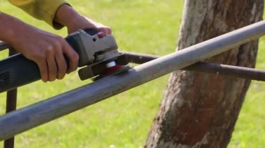 Metal öğüten işçiler, kıvılcımlı metal öğütme makinesi, metal testeresi. Metal çubuk. İnsan, sopadan makina yüzeyi ile çaprazlar. Paslanmaktan kurtul.