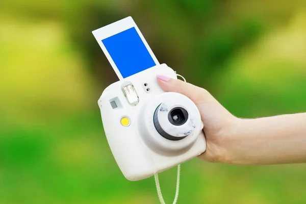 camera with instant printing in a female hand on a green backgro