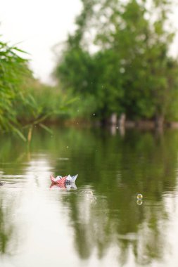 Bir kağıt tekne suya koyarak bir çocuk