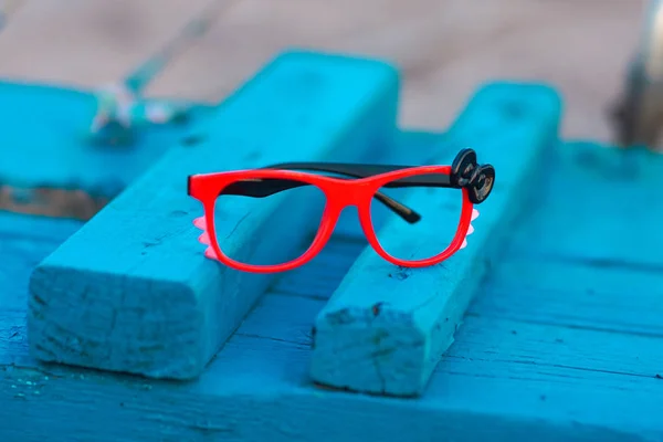 Óculos de imagem vermelho brilhante em um fundo de madeira azul — Fotografia de Stock