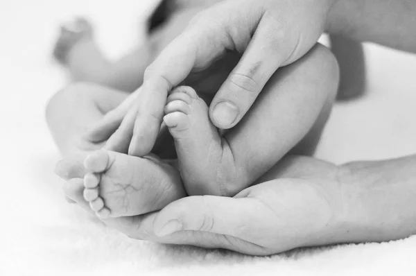 La main du père et de la mère tient le pied du nouveau-né — Photo