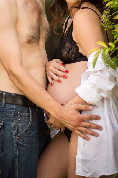 Беременная девушка обнимает свой желудок, светит солнце и зеленая трава. Концепция счастливой женщины и материнства . — стоковое фото