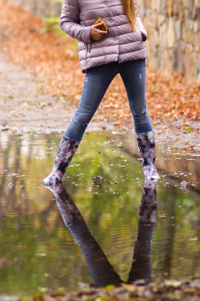 Menina alegre em botas de borracha pulando em poças após a chuva — Fotografia de Stock