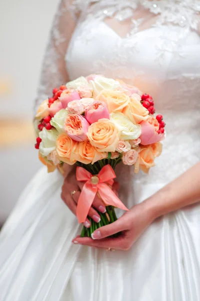 Noiva jovem em um belo vestido segurando um buquê nas mãos — Fotografia de Stock