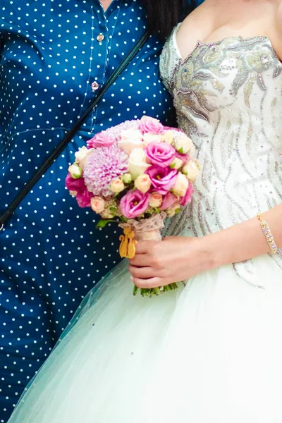 Jonge bruid in een mooie jurk met een boeket in handen — Stockfoto