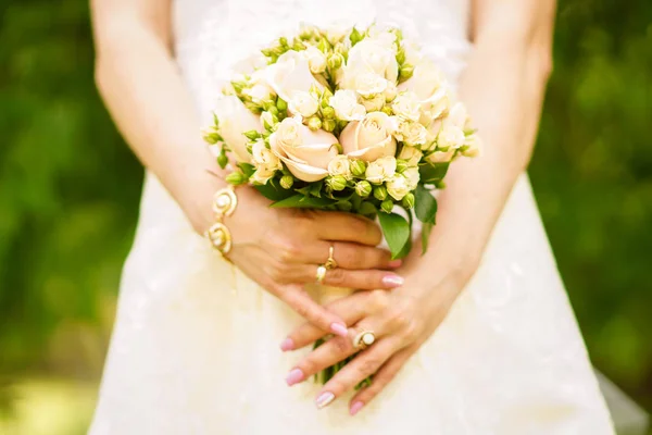Noiva jovem em um belo vestido segurando um buquê nas mãos — Fotografia de Stock
