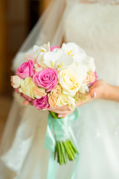 Young bride in a beautiful dress holding a bouquet in hands — Stock Photo, Image