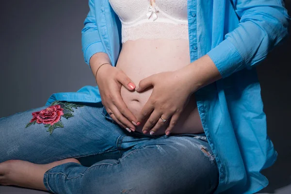 Jovem mulher grávida em antecipação de uma criança. fotos de estúdio em um fundo. conceito de maternidade feliz — Fotografia de Stock