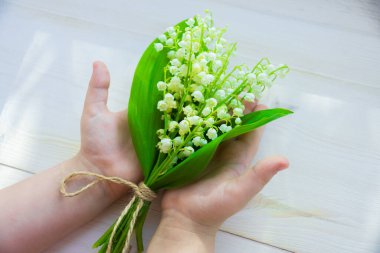 Vadideki zambak buketi beyaz bir ahşap arka planda ellerinde.